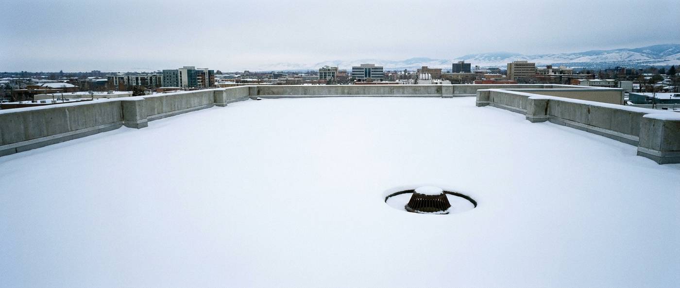 Flat commercial roof under deep even snow cover with parapet walls