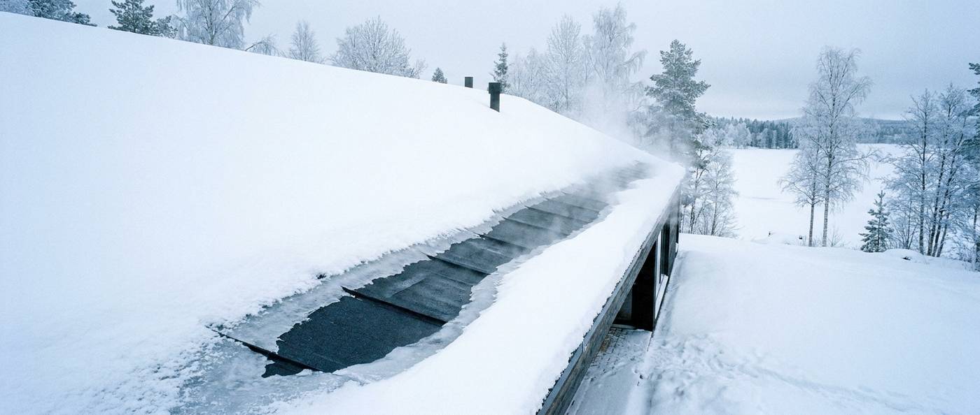 Steam rising from an ice-covered roof eave during ice dam removal